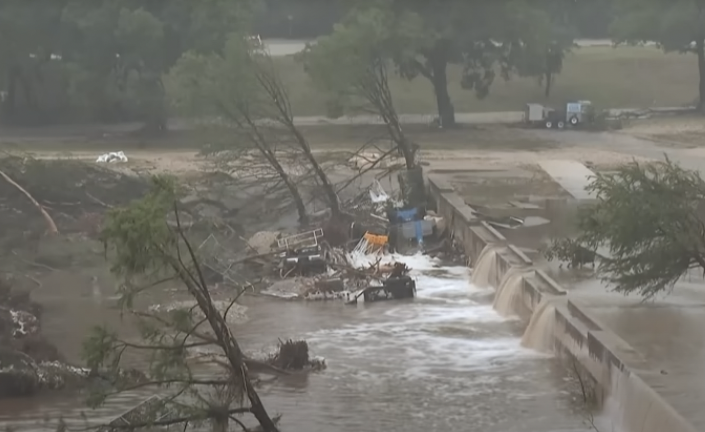 Vue d’une crue au Texas : arbres déracinés et amoncellement de débris bloqués contre un ouvrage en béton, lors des inondations de juillet 2025.